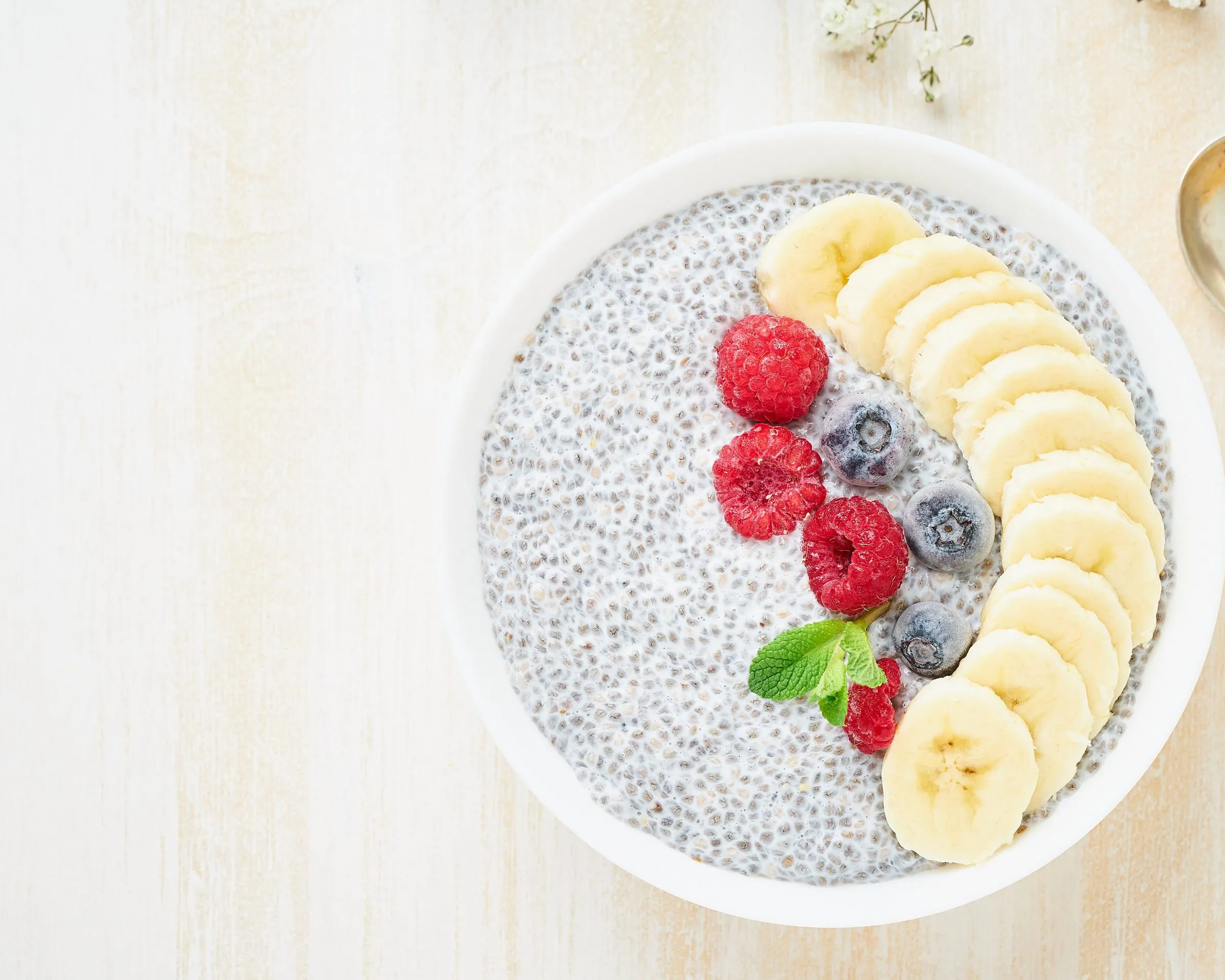 Een kom chiapudding met banaan, frambozen en blauwe bessen