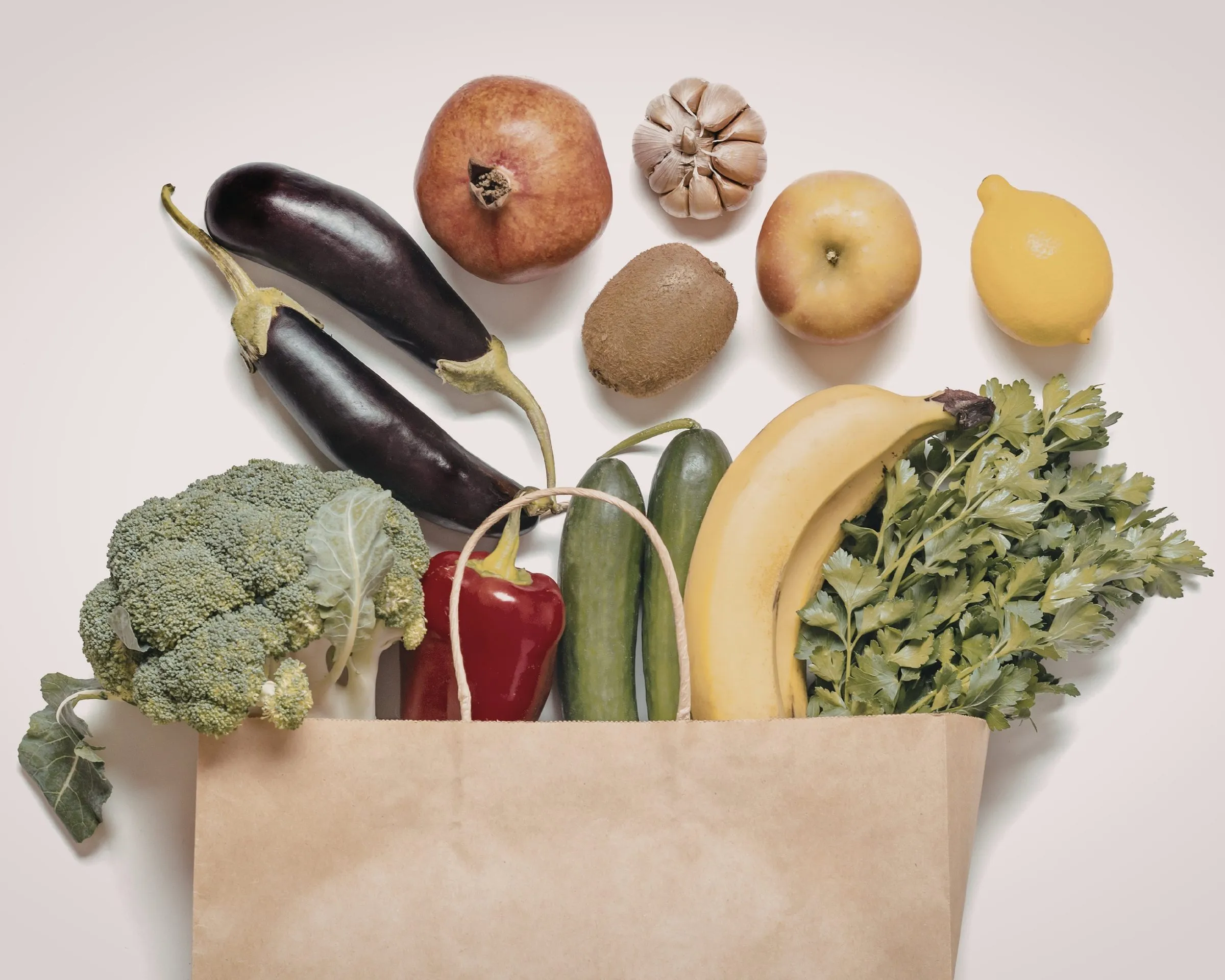 Een papieren boodschappentas gevuld met verse groente en fruit